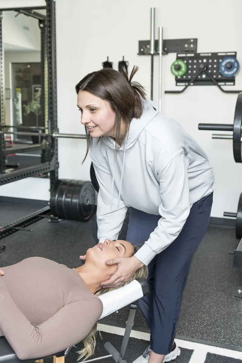Dr. Abby Dante leaning over a patient on a treatment table, cradling the patient's head and neck in both hands