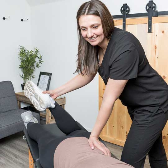 Dr. Abby Dante raising a patient's straight leg on the treatment table, one hand on the thigh to guide the stretch