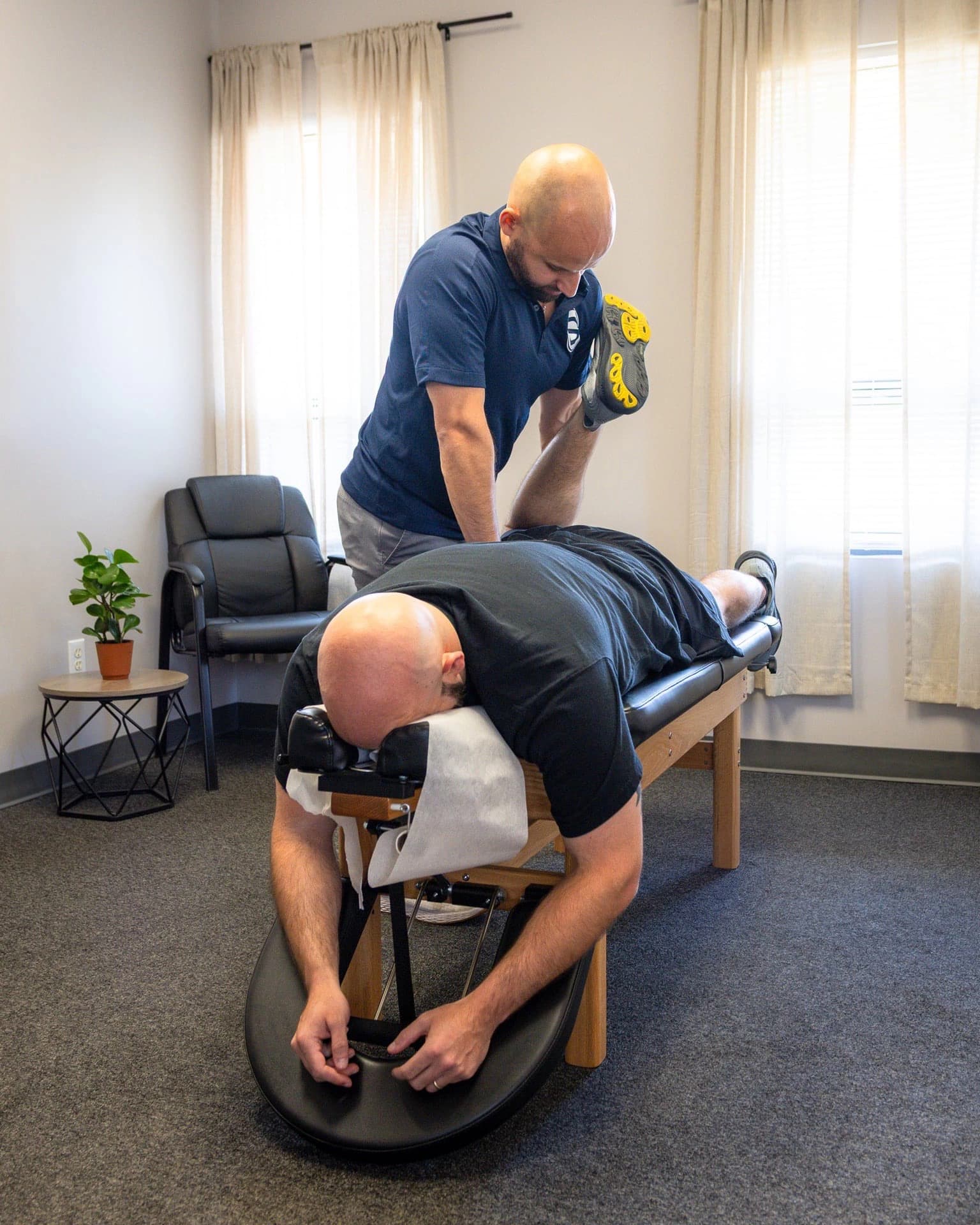 Dr. Dave Atlas bending the knee of a patient lying face down on a treatment table
